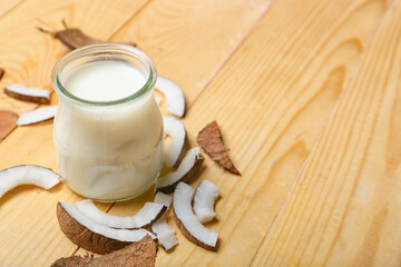 Glass of tasty coconut milk on wooden background