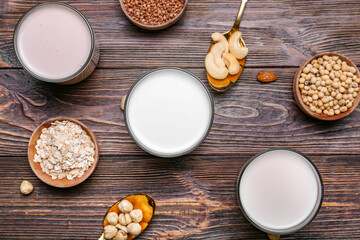 Glasses of different milk on wooden background