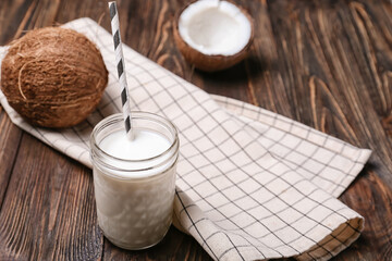 Jar of tasty coconut milk on wooden background