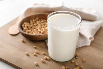 Glass of tasty soy milk on wooden board
