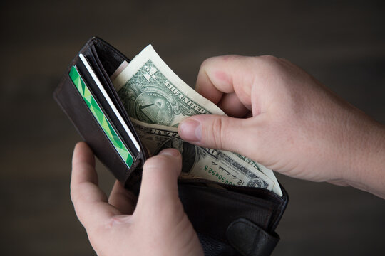 An Empty Wallet With A Small Amount Of Money In The Hands Of A Working Man. Poverty Concept