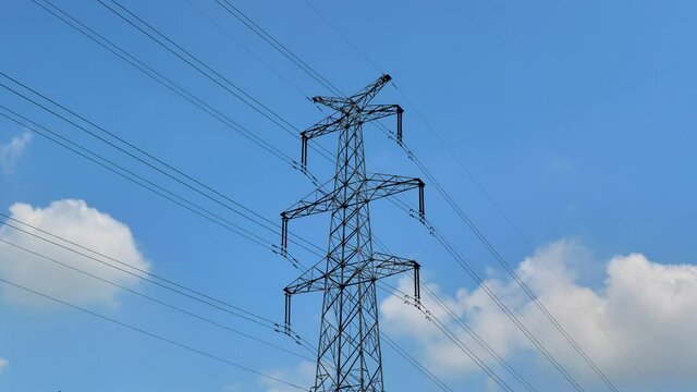 Timelapse video of high voltage power lines and tall electricity pylon against the sky and clouds