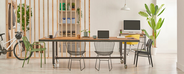 Modern and decorative office interior style with wooden long table, black metal chair, computer and...