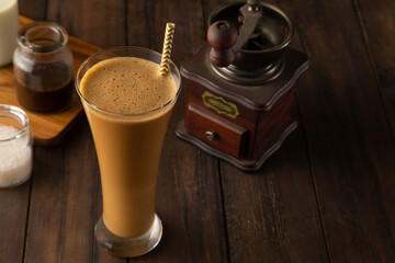  A tall Glass of Cold Coffee, with fresh milk and a coffee grinder 	