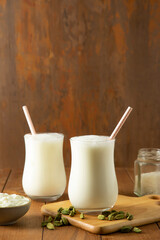 Buttermilk in glasses On wooden Table with cardamom	