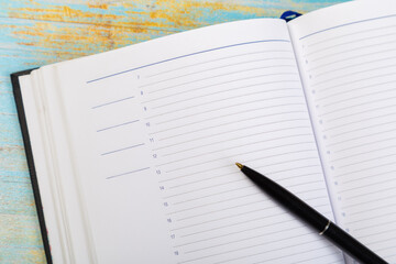 colored notepads with ballpoint pen on blue wooden background