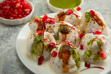 Dahi Vada or Dahi Bhalla a popular Indian snack is fried lentil dumplings, topped with curd, sweet and green chutney and spices	