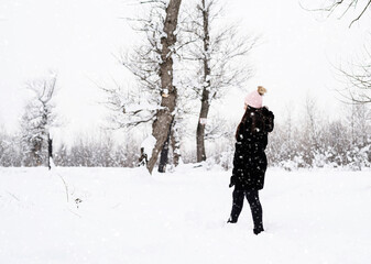 Rear view of brunette woman walking in snowy park in snowfall