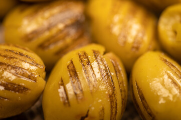Green marinated olives, pitted, roasted on the grill. The texture of the surface. Close-up,...