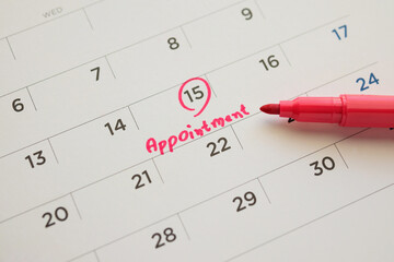 Red color marker pen pointing at important appointment schedule on white calendar page date close up