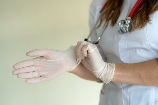 Female doctor puts on protective surgical gloves before hard work day in clinic