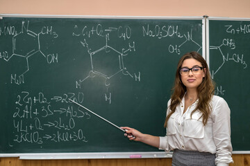 Chemistry teacher in front of a chalkboard explain a lesson.  Interesting and fascinating