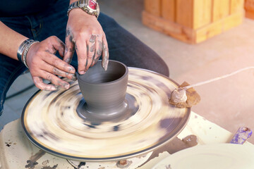 Hands of a potter creating an earthen bowl on the circle