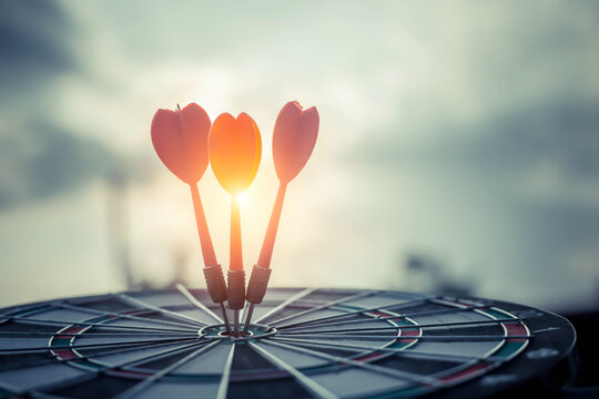 Close up shot of the dart arrow hit on bulleyes of dartboard to represent that the business reached the target  with dark tone picture style. Target and goal as concept.