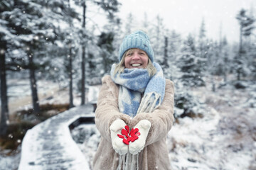 lachende Frau mit roten Stoffherzen im Winterwald