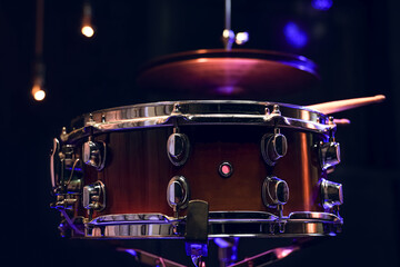 Snare drum and drumsticks close up in dark.