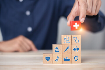 Hand arranging wood block stacking with icon healthcare medical, Health insurance - concept.