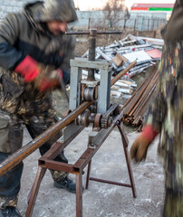 Workers bending metal at a construction site. Technology