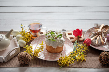 Easter composition with cake, tea, flowers, eggs and decoration details.