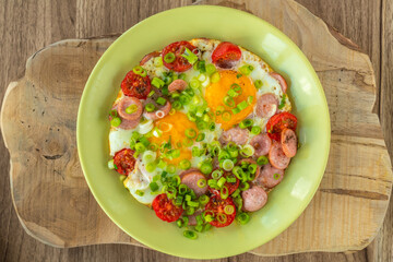 Fried eggs with sausages, tomatoes and vegetables.