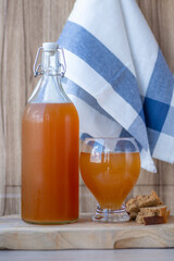 Traditional Russian cold rye drink Kvass in a glass and a jug on a wooden table.