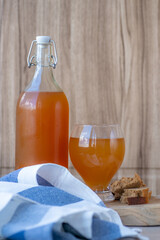 Traditional Russian cold rye drink Kvass in a glass and a jug on a wooden table.