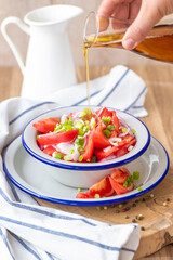 Fresh ripe juicy red tomato salad with green onions and vegetable oil.