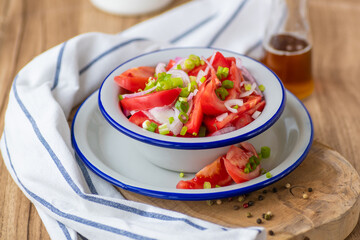 Fresh ripe juicy red tomato salad with green onions and vegetable oil.