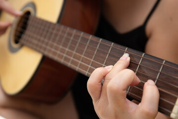 Fototapeta na wymiar Close up of female hand playing guitar at home