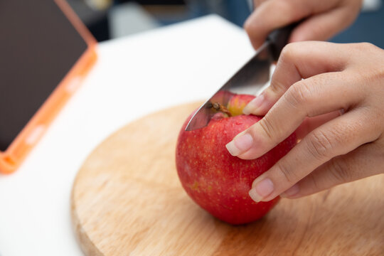 Female Using Knife To Cut Apple On The Cut Board 