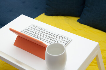 work from home concept. Digital tablet, wireless keyboard and coffee cup on the table on the sofa at home 