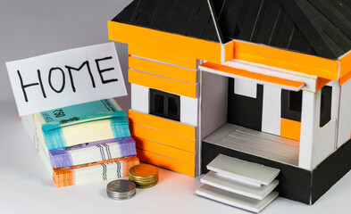 High angle shot of a toy house with money notes and coin on the side showing home loan concept.