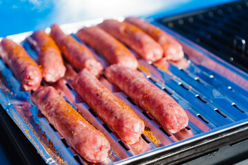 Sausages meat grilling on gas grill