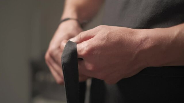 Slow motion shot: Men's hands tie a belt on a black jacket. 4k