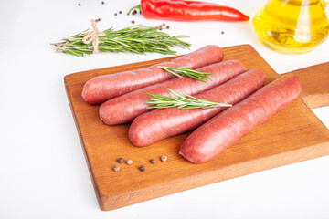 Raw meat beef sausages for grill and spicy, herbs rosemary, pepper, salt on table
