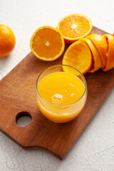 tarocco oranges on cutting board with glass of orange juice. on light background