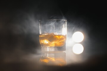 whiskey with ice on black background with smoke