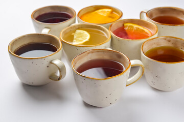 White tea, green tea, black tea, fruit and berry tea in ceramic cups. Many cups over white...