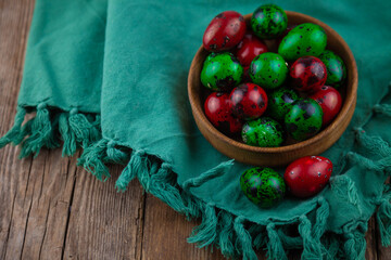 Easter colored eggs. Quail egg of green and red color on a wooden plate background. Happy Easter greeting card. Place for your text. Food on the background.