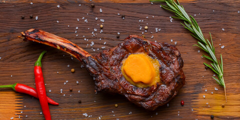Barbecue tomahawk steak with spices served on a rustic wooden board over wooden background.