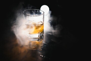 whiskey with ice on black background with smoke