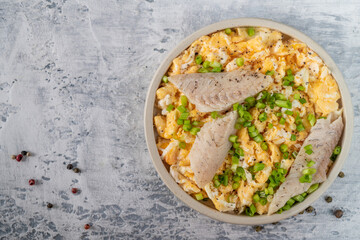 Fried eggs with smoked white fish fillet and fresh green onions.