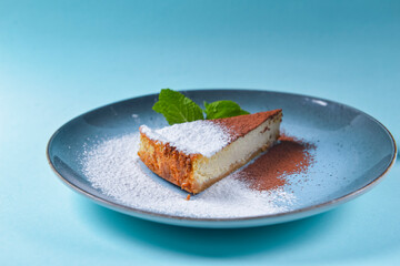 Slice of Plain New York Cheesecake on blue plate over blue background. Close up.