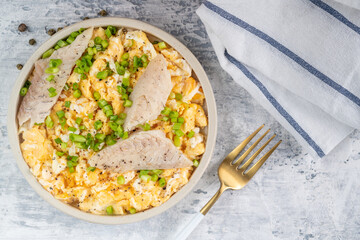 Fried eggs with smoked white fish fillet and fresh green onions.