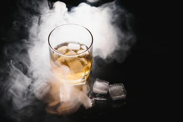 whiskey with ice on black background with smoke