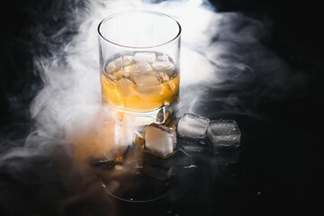 whiskey with ice on black background with smoke