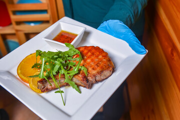 Waiter serving bbq grilled steak in restaurant or diner. Eating out concept.