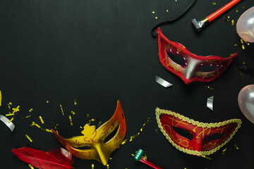 Table top view aerial image of beautiful colorful carnival festival background.Flat lay accessory object the several mask & decor confetti on modern black wooden at home office desk studio.copy space.