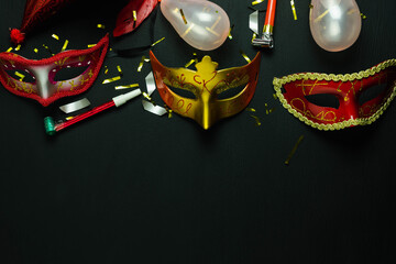 Table top view aerial image of beautiful colorful carnival festival background.Flat lay accessory object the several mask & decor confetti on modern black wooden at home office desk studio.copy space.