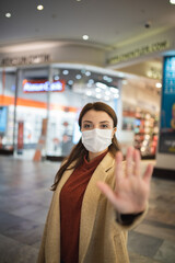 Fototapeta na wymiar Beautiful girl wearing protective medical mask and fashionable clothes holds hand up as stop sign New normal lifestyle concept.